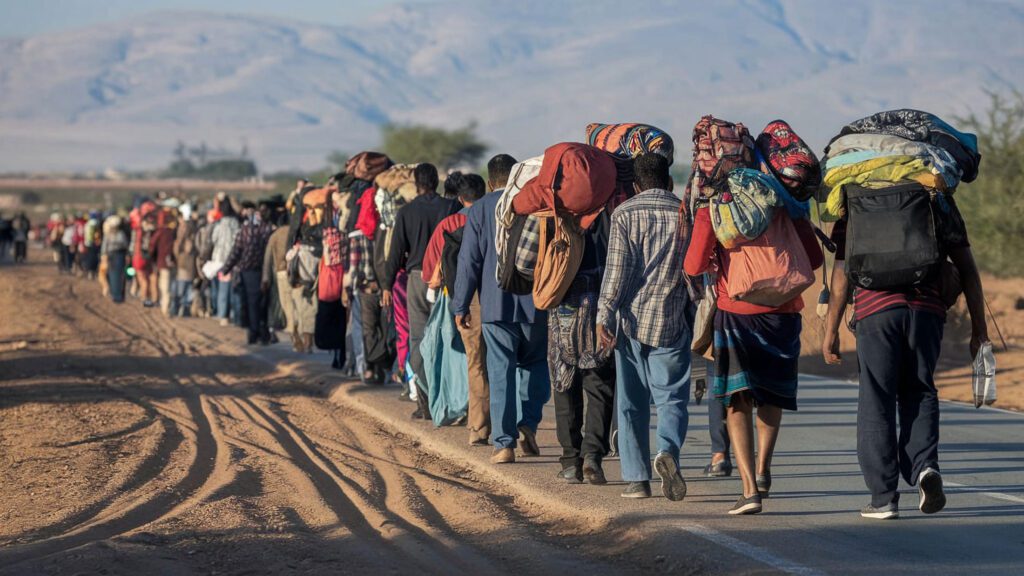 Eine Gruppe Flüchtlinge laufen am Straßenrand